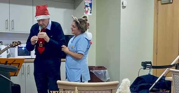 Male resident playing thin whistle at Christmas Party