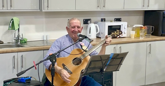 Brian on the guitar singing into microphone